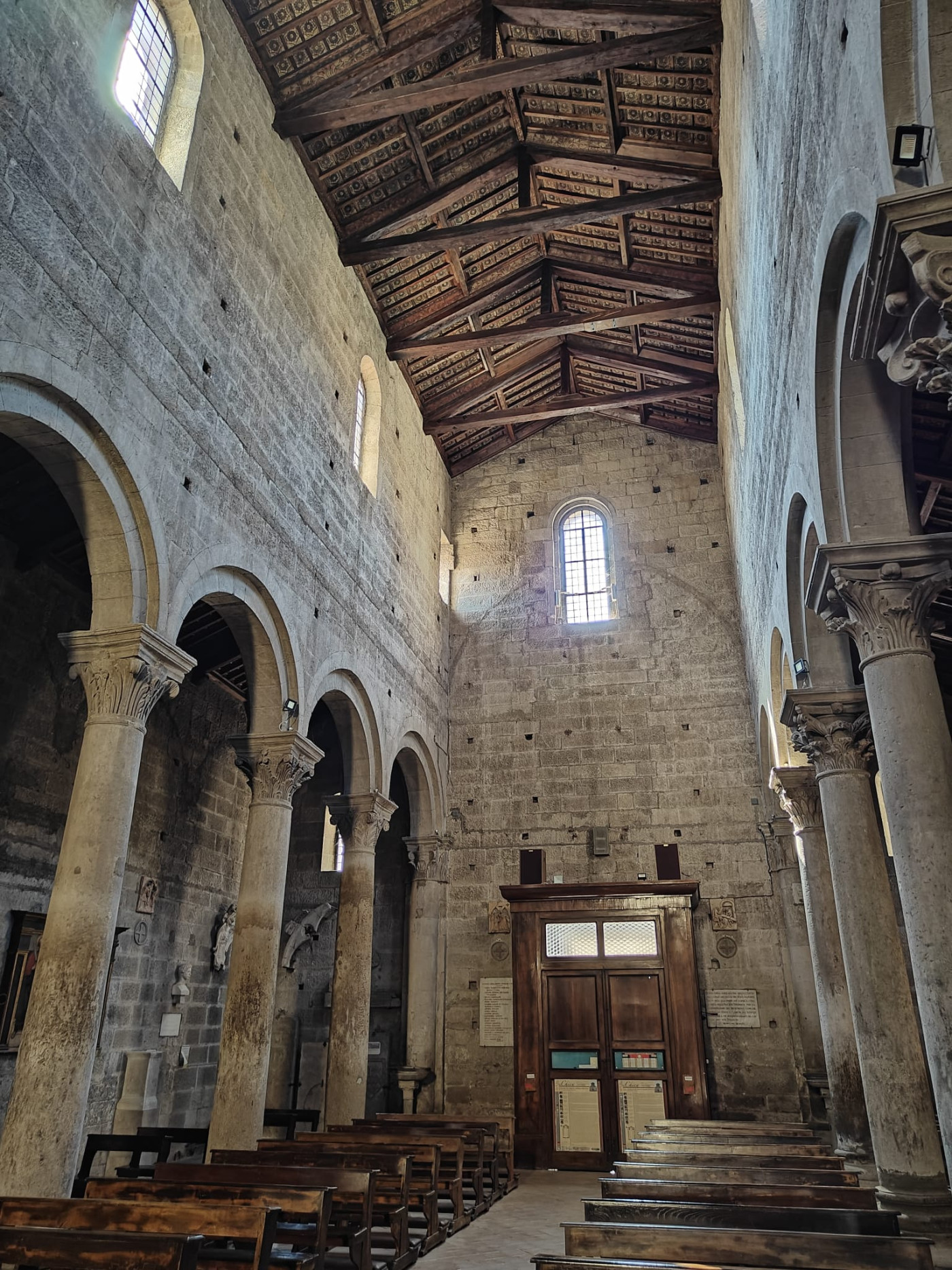 Scorcio della navata centrale in direzione della controfacciata l'armonico ritmo dei sostegni romanici guida lo sguardo verso le maestose capriate lignee che coronano l'aula.